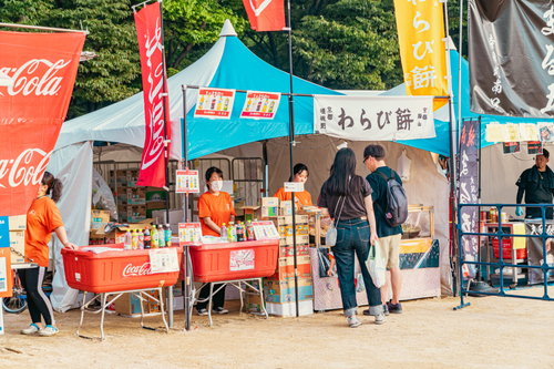 Free Cultural festival with vibrant food stalls and visitors browsing in a lively outdoor market. Stock Photo