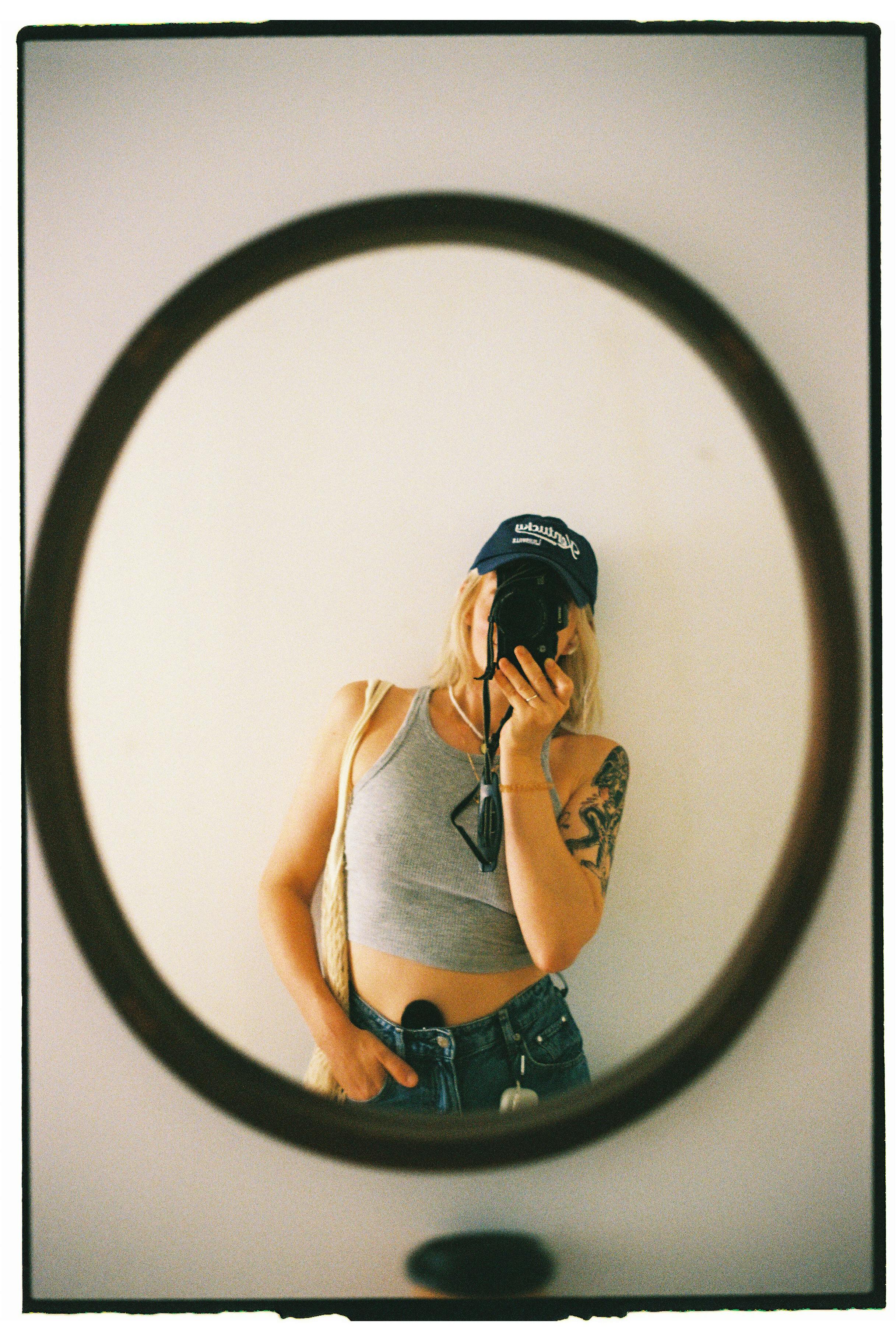 Woman takes a casual mirror selfie in a stylish outfit, capturing a relaxed vibe.