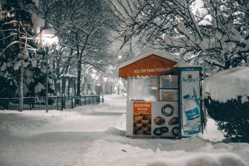 Free Winter night at Kultur Park, Konya with snow-covered trees and a quaint food stall. Stock Photo
