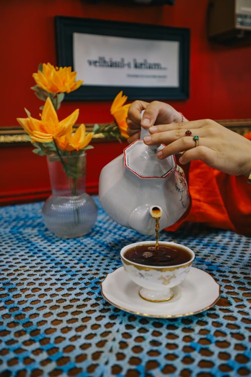 Free A person pouring tea from a classic teapot into a cup, set against a vibrant cafe backdrop in Istanbul. Stock Photo