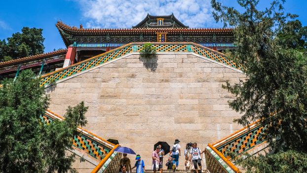 在充满活力的夏日天空下，游客们探索着北京颐和园的历史建筑