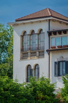 Elegant Mediterranean villa with terracotta roof and arched windows in a sunny setting.