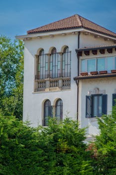 Elegant Mediterranean style house with lush greenery and large windows.