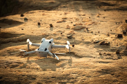 Aerial drone resting on rugged sandy ground at sunrise, capturing serene technology in nature.