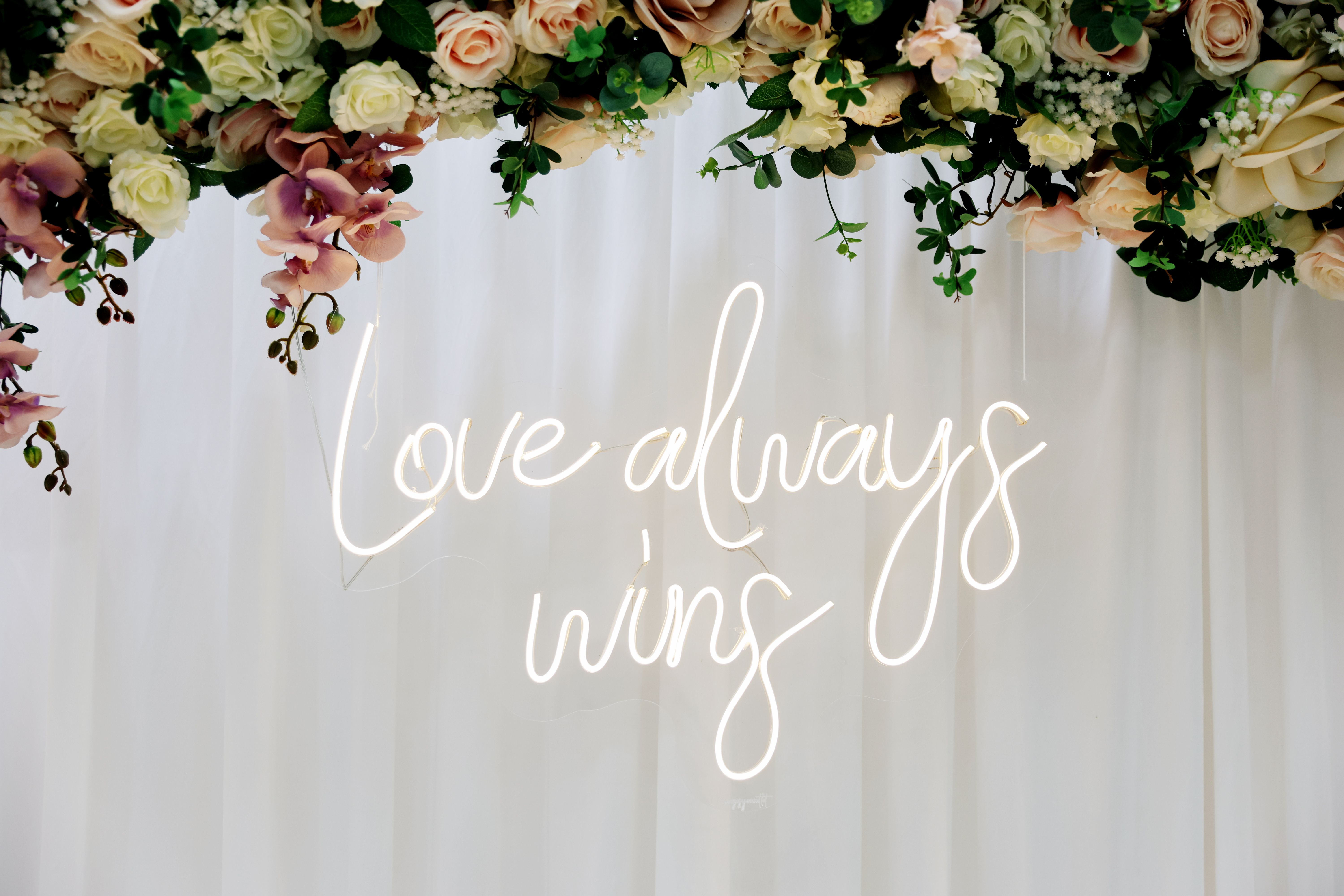 Floral engagement backdrop with a glowing neon sign