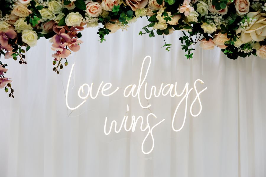 Floral engagement backdrop with a glowing neon sign