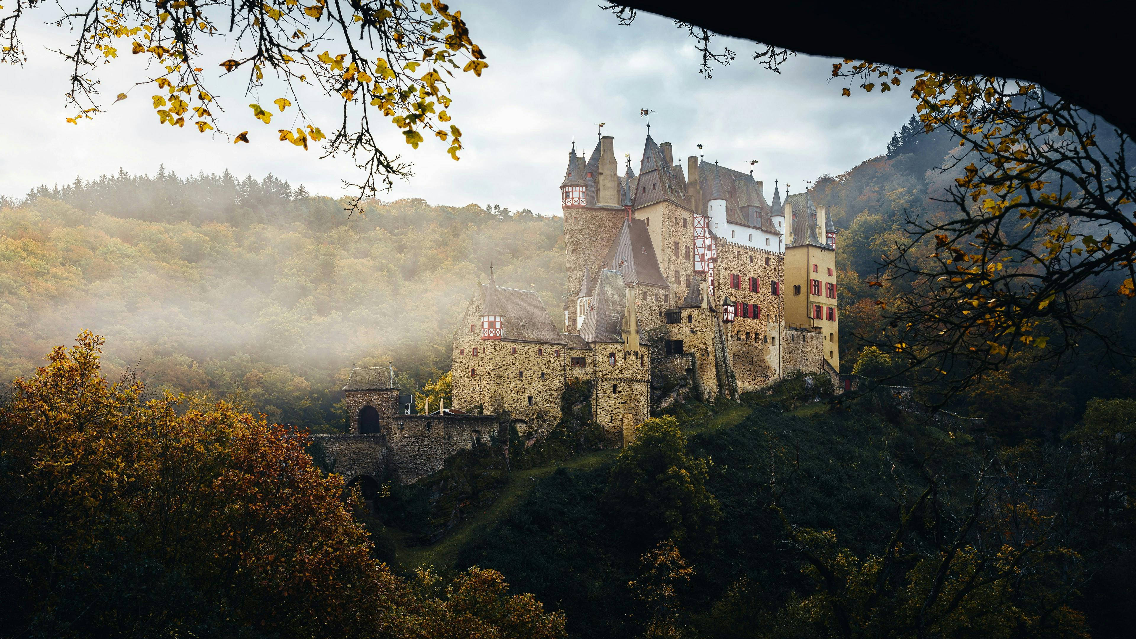 Eltz Castle nestled in colorful autumn foliage with mist, Germany. - Castillo Eltz