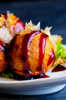 Close-up of mouthwatering takoyaki drizzled with a rich sauce, perfect for food enthusiasts.
