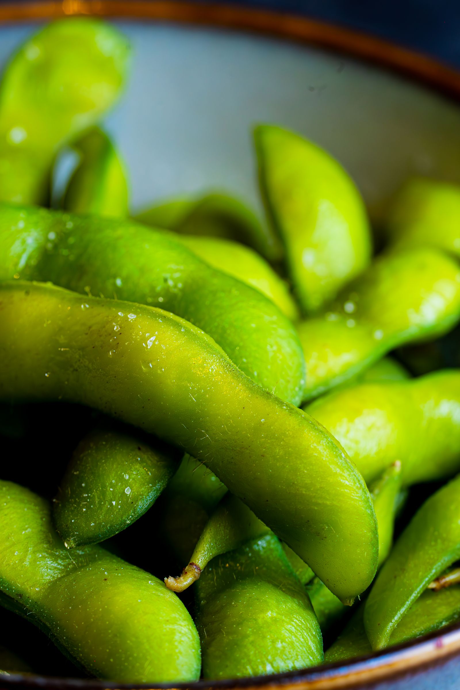 Close-up of bright green cooked soybeans in a white ceramic bowl