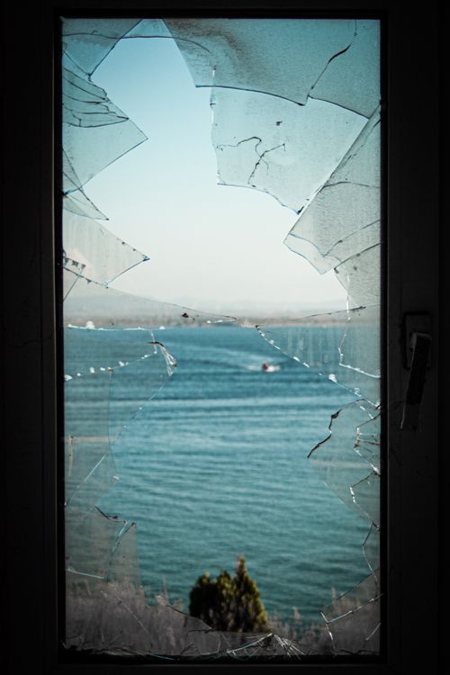 Free A tranquil lake view framed by shards of broken glass. Stock Photo
