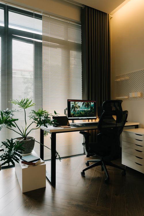 Free A stylish home office featuring a sleek desk, ergonomic chair, and potted plants under natural light. Stock Photo