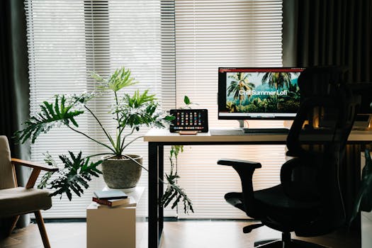 Stylish home office featuring large plant, computer setup, and minimalist aesthetic.