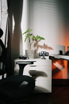 Stylish home office setup with a potted plant, digital clock, and sleek furniture in a contemporary setting.