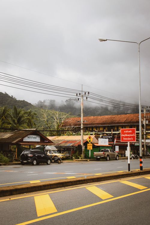 Free A bustling street view in Khao Lak, Thailand, showcasing local architecture under cloudy skies. Stock Photo