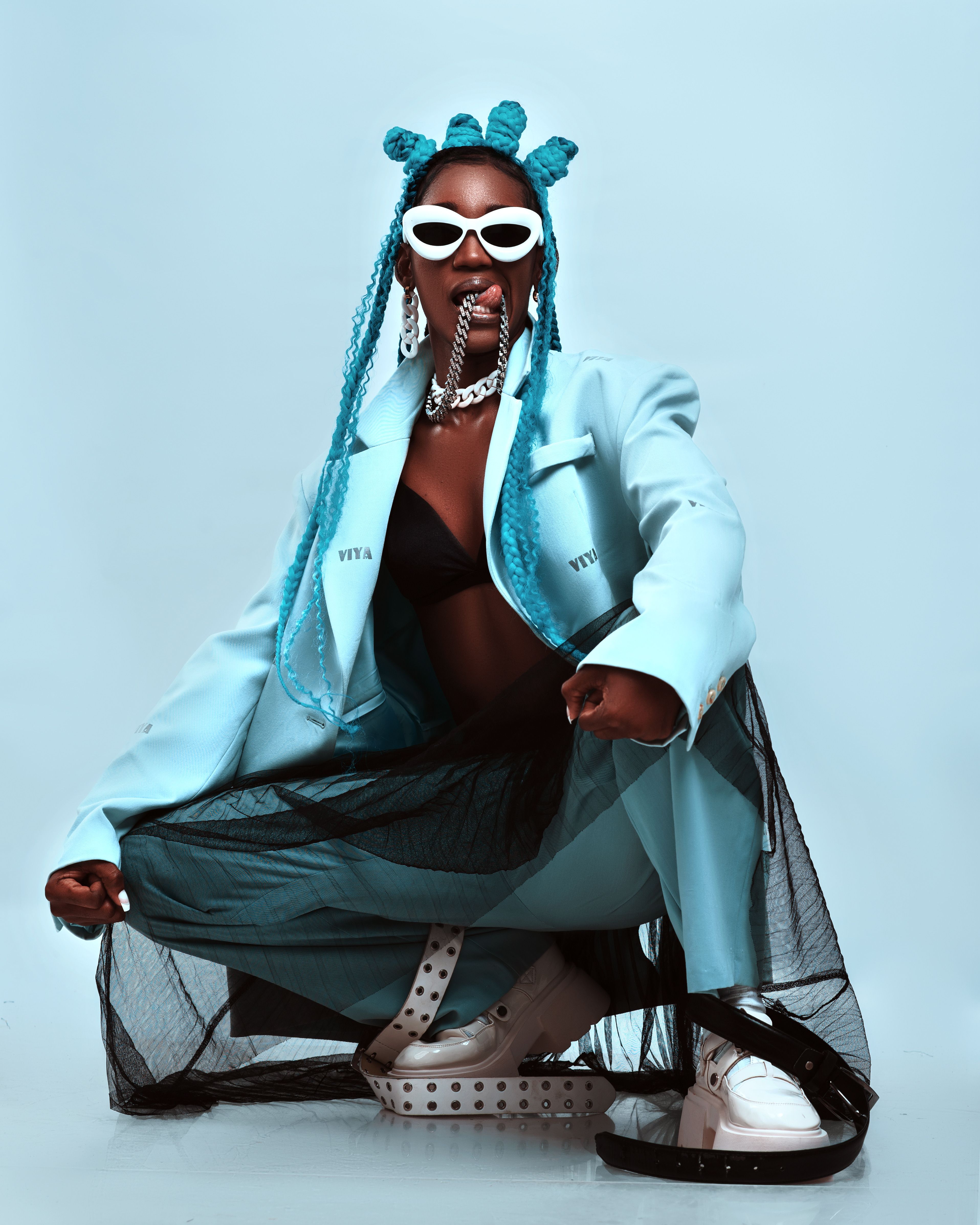 A stylish woman in a blue outfit and bold accessories showcases Afrocentric fashion in Luanda, Angola.