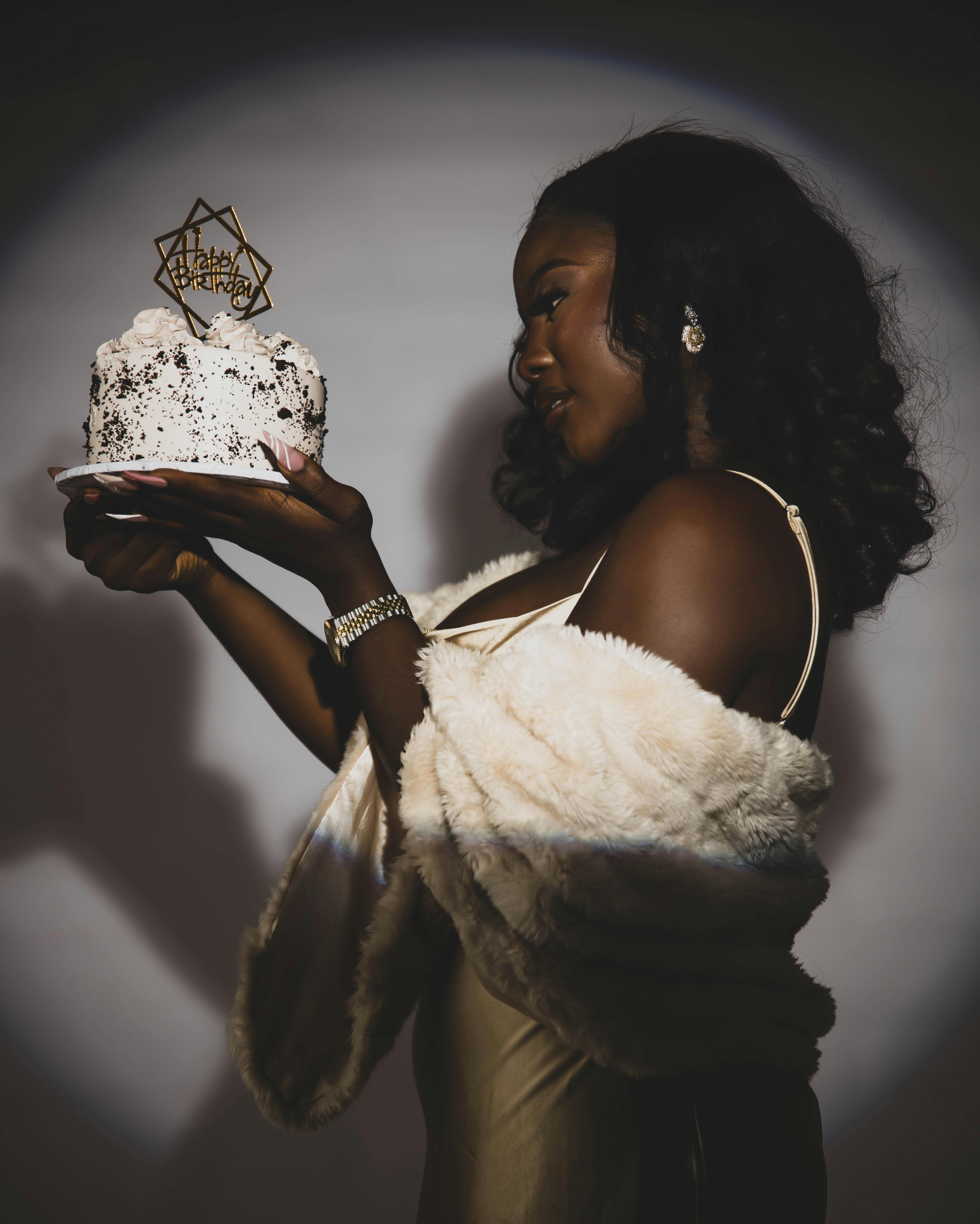 Free Woman holding birthday cake in elegant attire, celebrating in style. Stock Photo