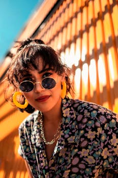 一位穿着花卉衬衫、搭配活力配饰的时尚女性，在橙色背景下自信地摆出姿势