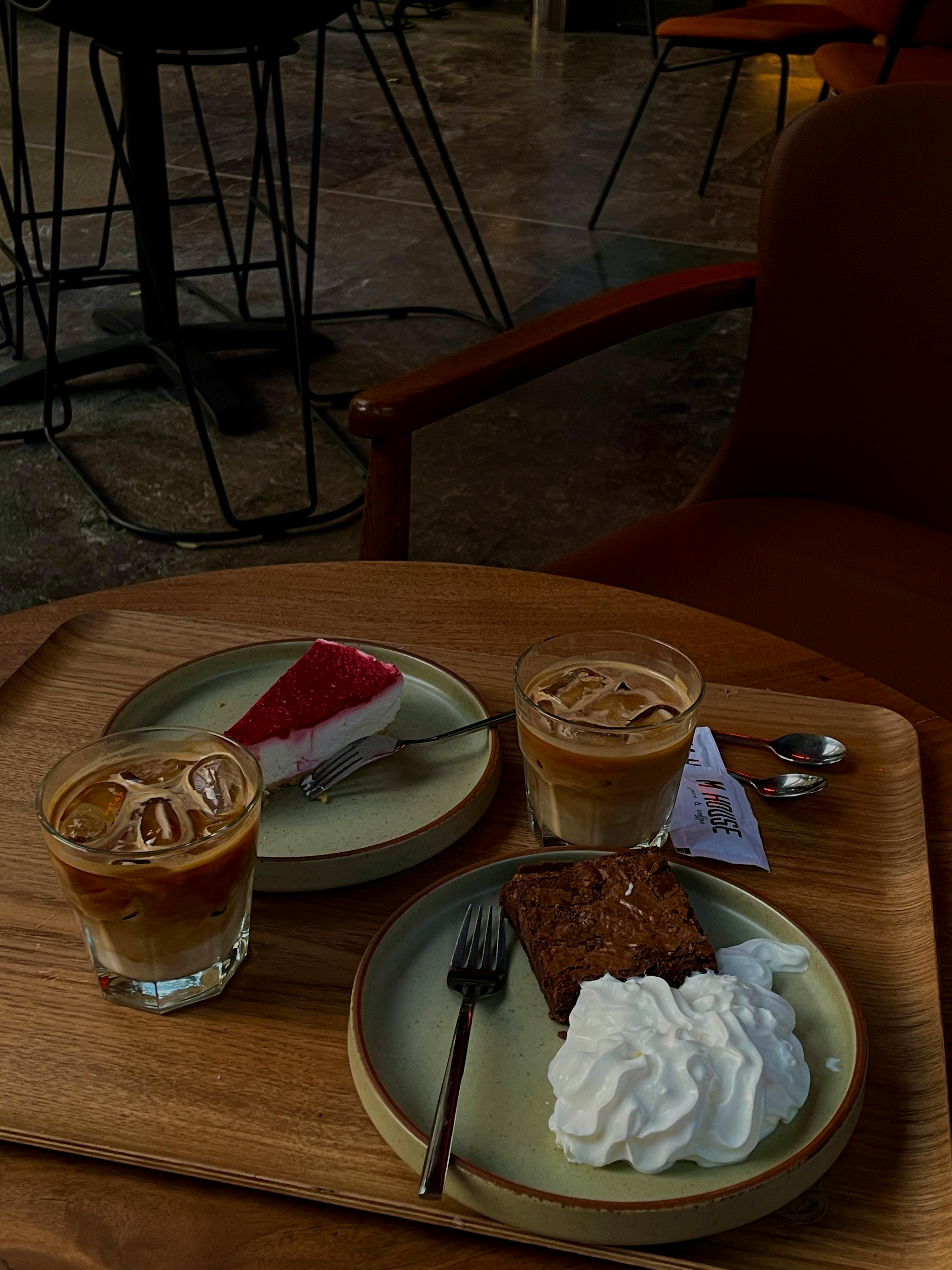 Inviting café scene with iced coffee, cake, and dessert on a wooden table.
