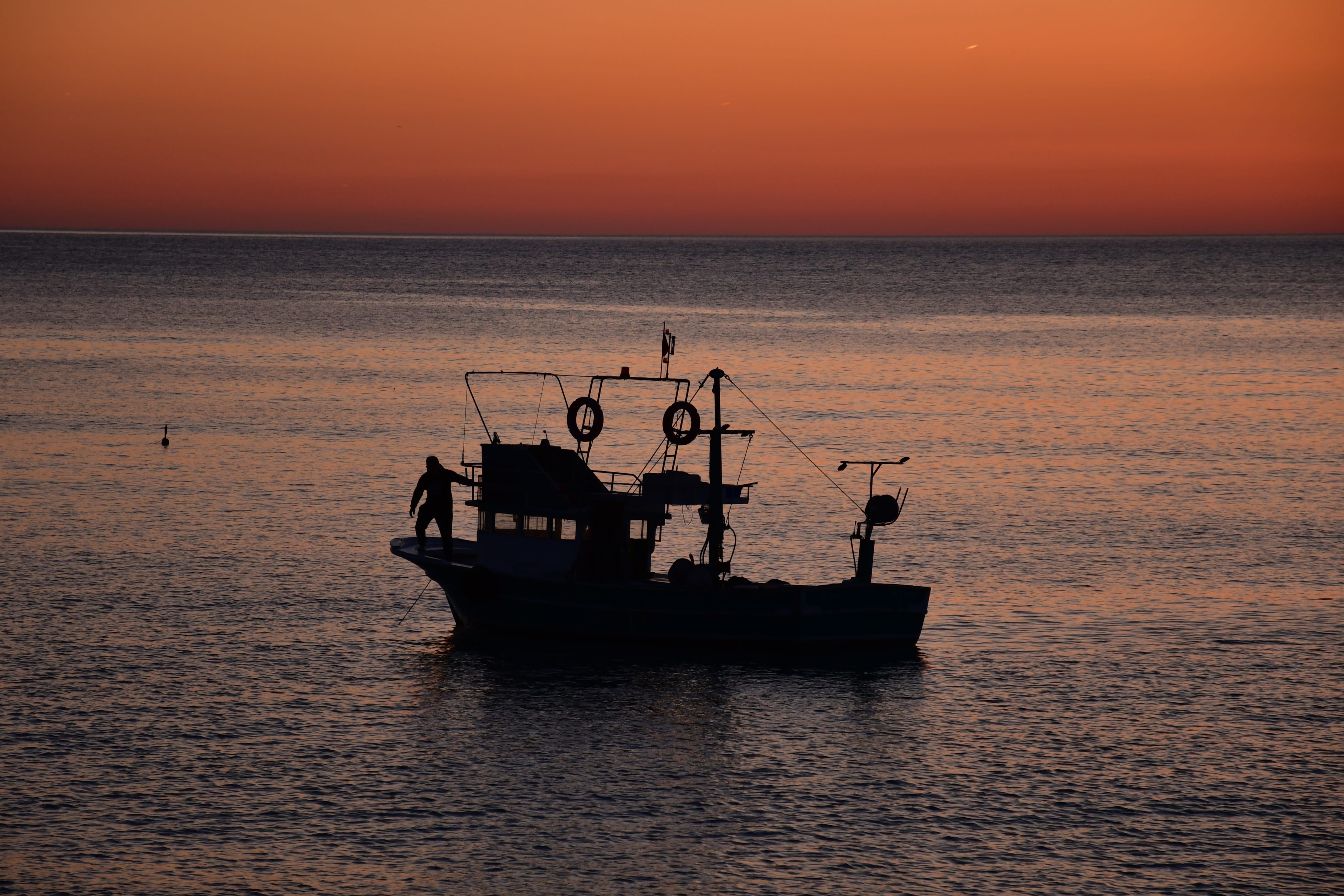Silhouette of Fishing Boat at Sunset on Calm Sea · Free Stock Photo