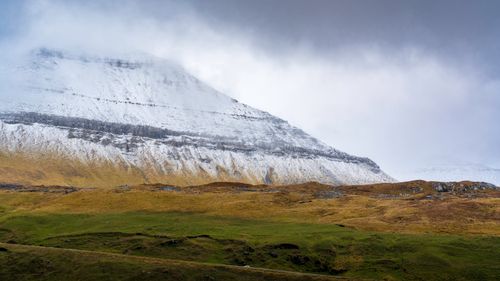 Free Majestic view of snow-capped mountains and green plains under a cloudy sky. Stock Photo
