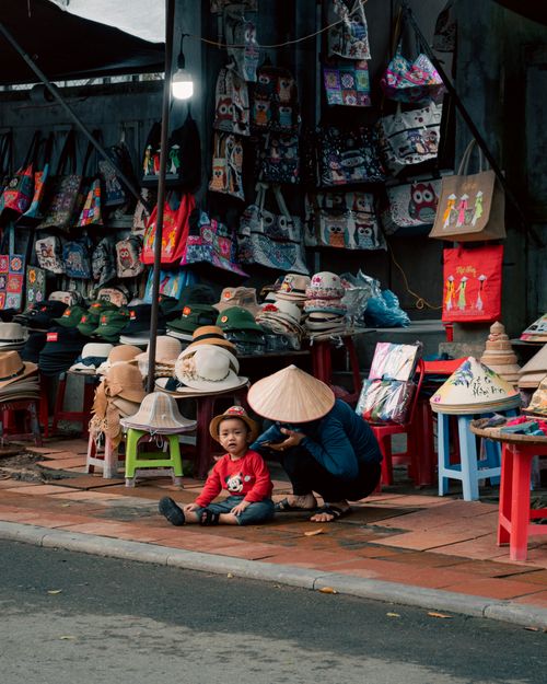 Free A colorful street market in Vietnam displaying hats and bags with locals enjoying the day. Stock Photo