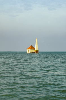 A solitary lighthouse stands against the serene blue waters of Gopalpur, India.