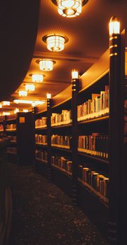 A quiet library aisle with glowing lights and shelves full of books.