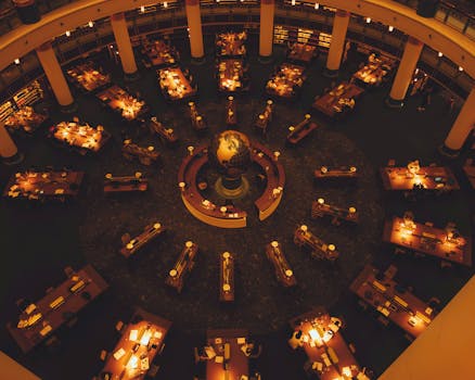 Round library interior with warm lighting and central globe viewed from above.