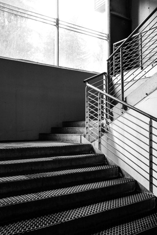 Free Black and white image of a contemporary industrial staircase with a metal railing. Stock Photo
