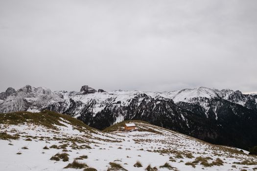 Captivating winter scene featuring snow-covered mountains and a small wooden cabin in Canazei, Italy.
