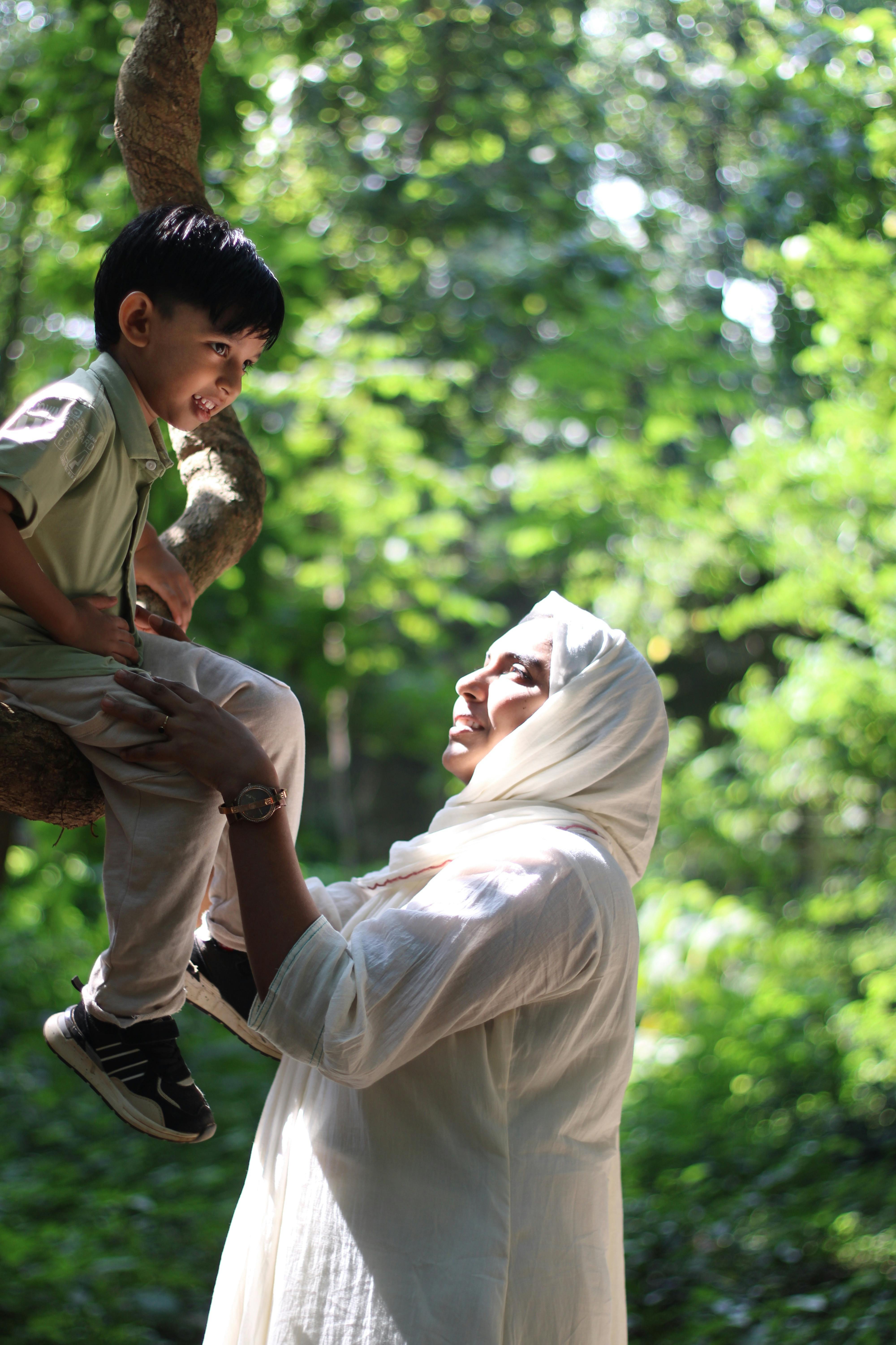A heartfelt moment between a mother and child in a sunlit forest in Nilambur, India.