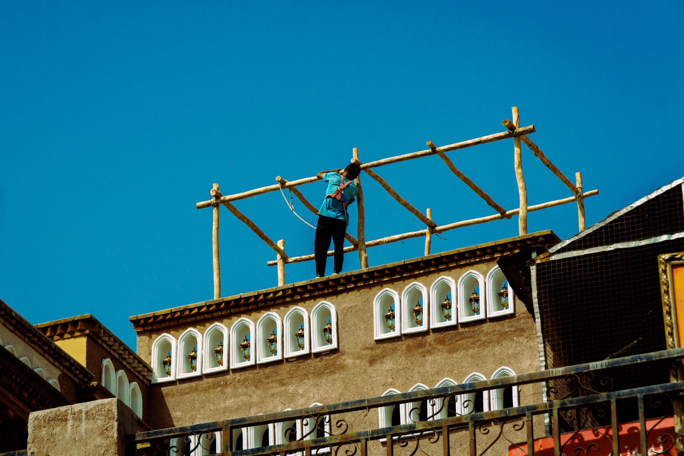 Man Building Things Man Building Wooden Structure on Rooftop · Free Stock Photo