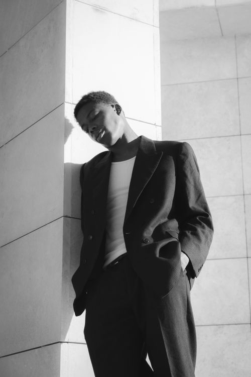 Free Stylish black and white portrait of a man in a suit leaning on a wall. Stock Photo