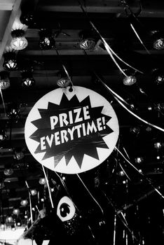 Black and white photo of a carnival sign that reads 'Prize Everytime!' amidst lights and ribbons.