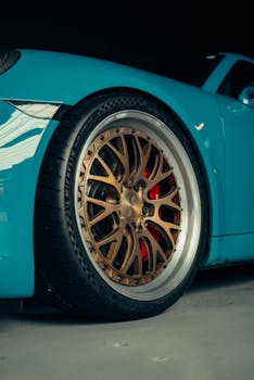 Detailed view of a bronze custom wheel on a sleek blue sports car indoors.