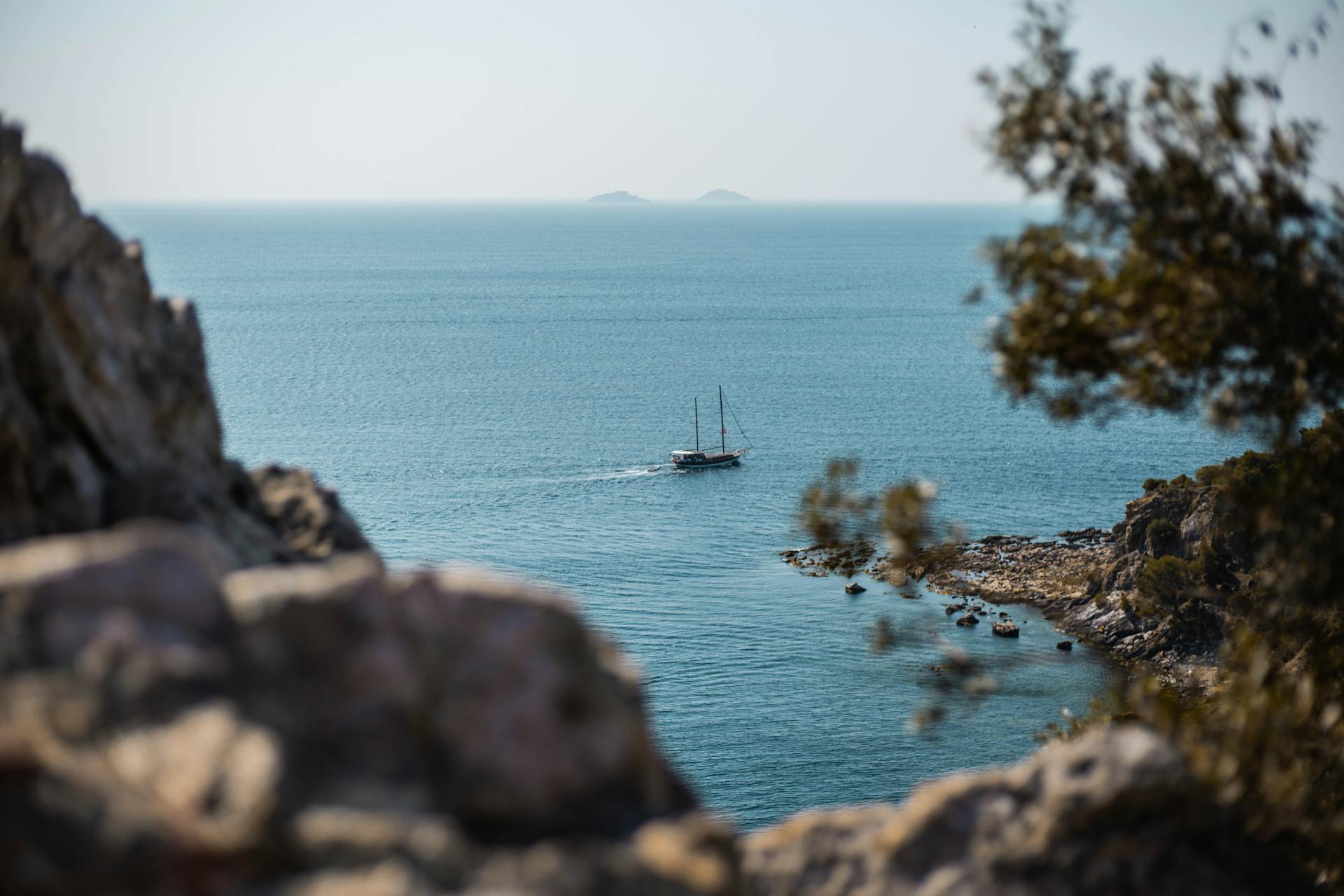 A sailing boat cruises through a scenic seascape off the Turkish coast, framed by natural rocks.