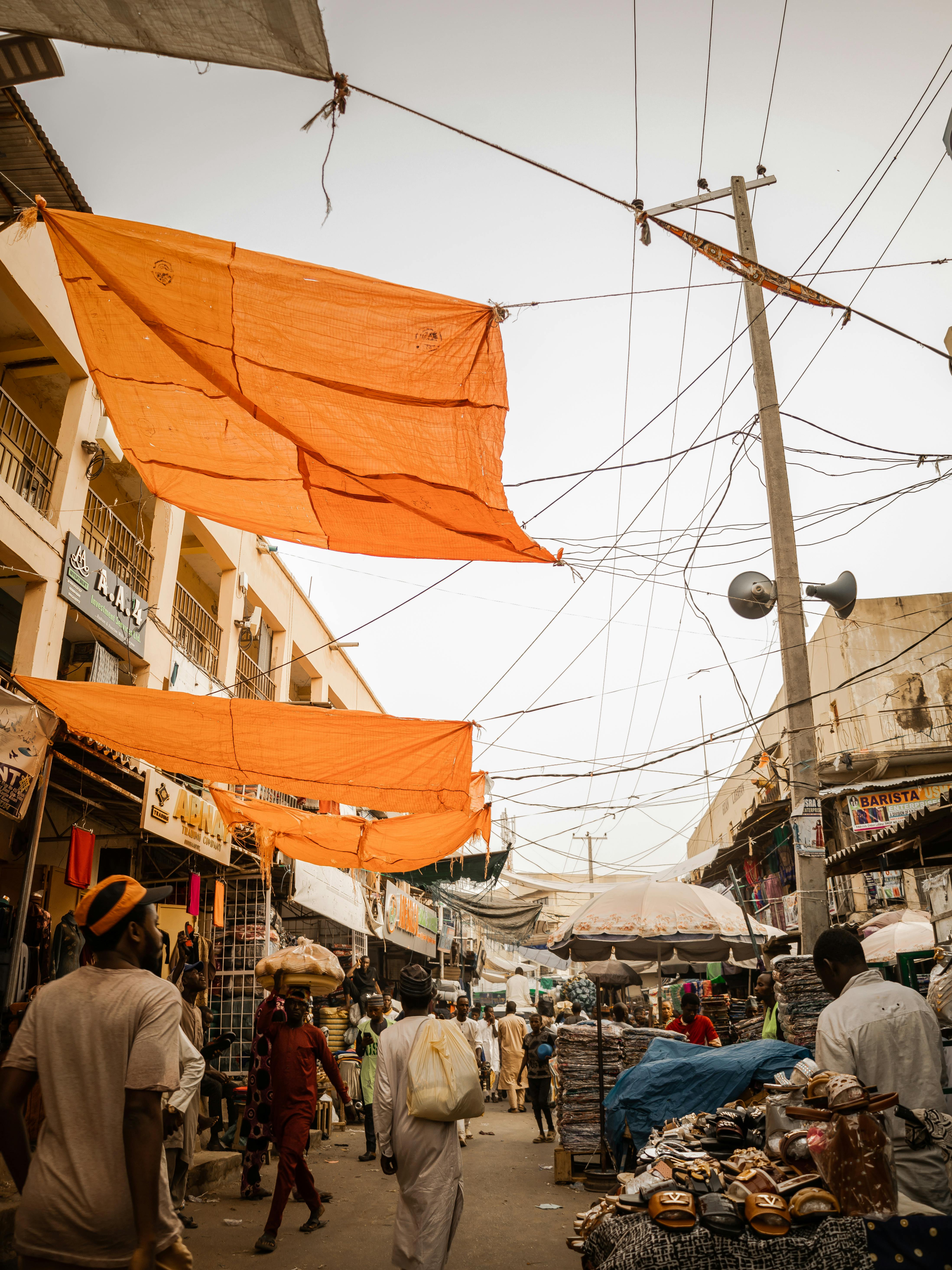 Lively market street in Nigeria with vibrant canopies and diverse people shopping.