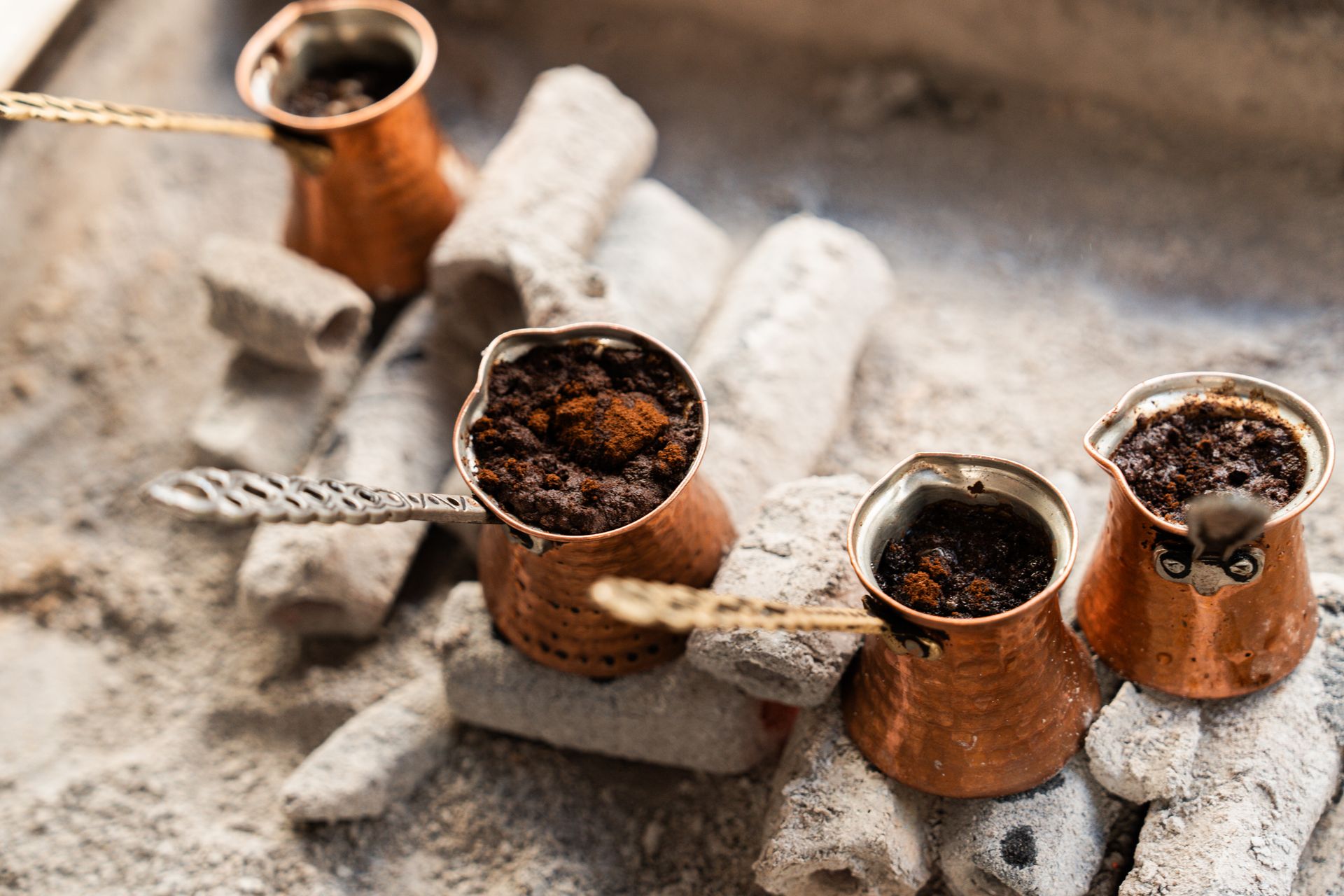 Copper pots brewing Turkish coffee over hot coals in İstanbul, Türkiye.