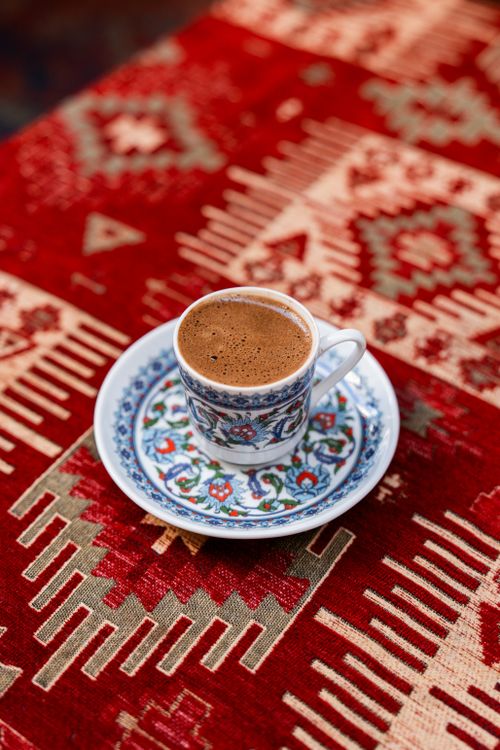 Free A cup of Turkish coffee served on an ornate saucer on a vibrant patterned tablecloth. Stock Photo