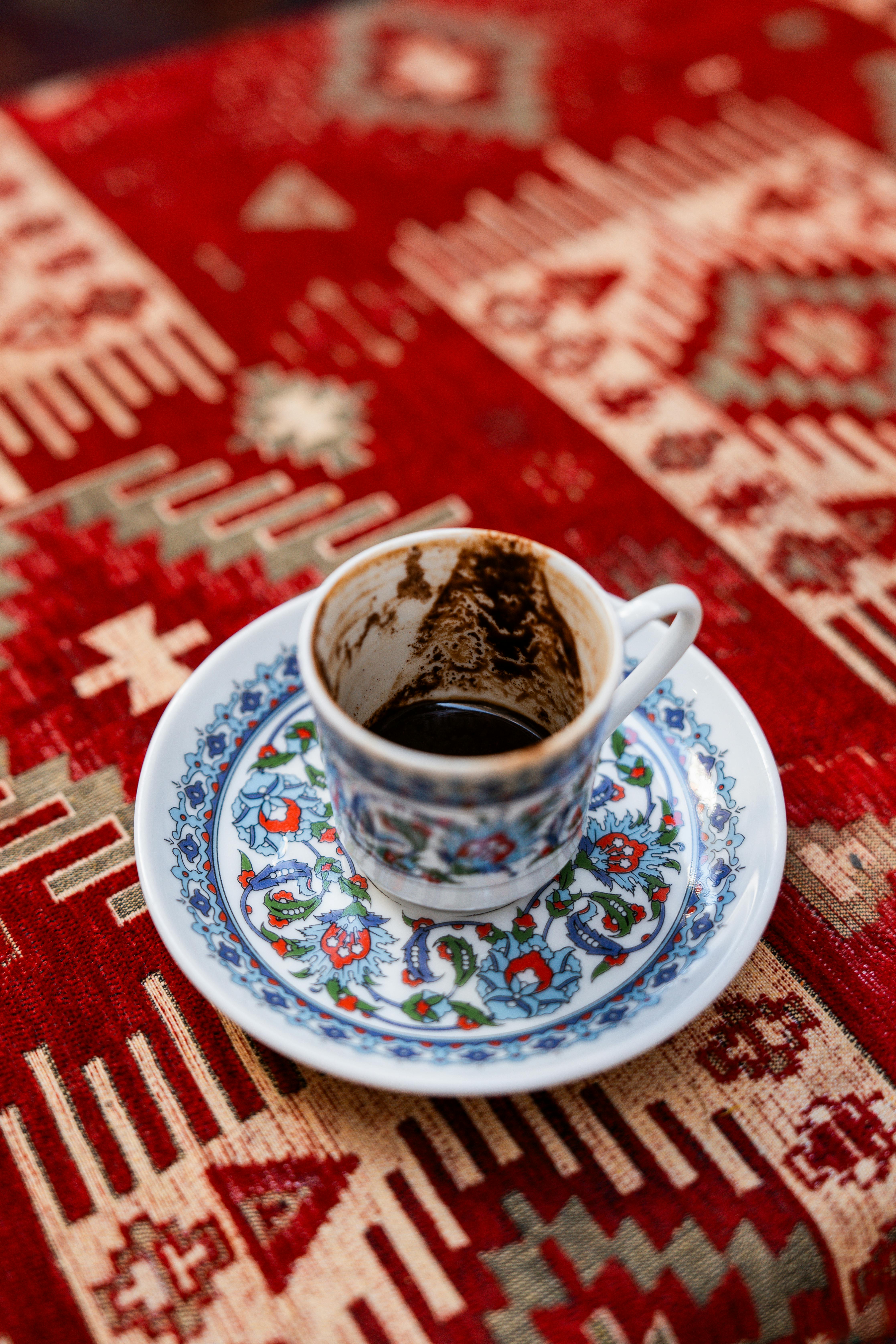 A detailed Turkish coffee cup with an intricate design on a traditional rug in Istanbul.