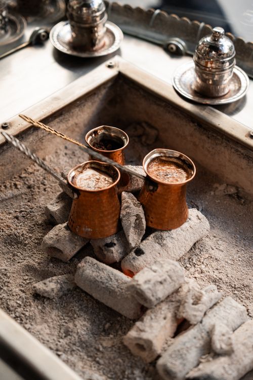 Free Turkish coffee being brewed in copper pots on sand. Authentic Istanbul experience. Stock Photo