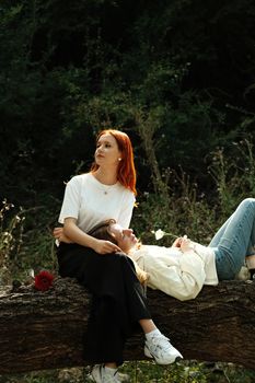 Two women enjoying a peaceful moment in nature, one with red hair and floral accents.