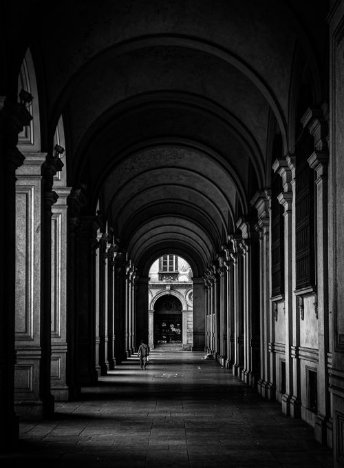 Free A scenic black and white photo of a grand arched corridor with a lone figure. Stock Photo