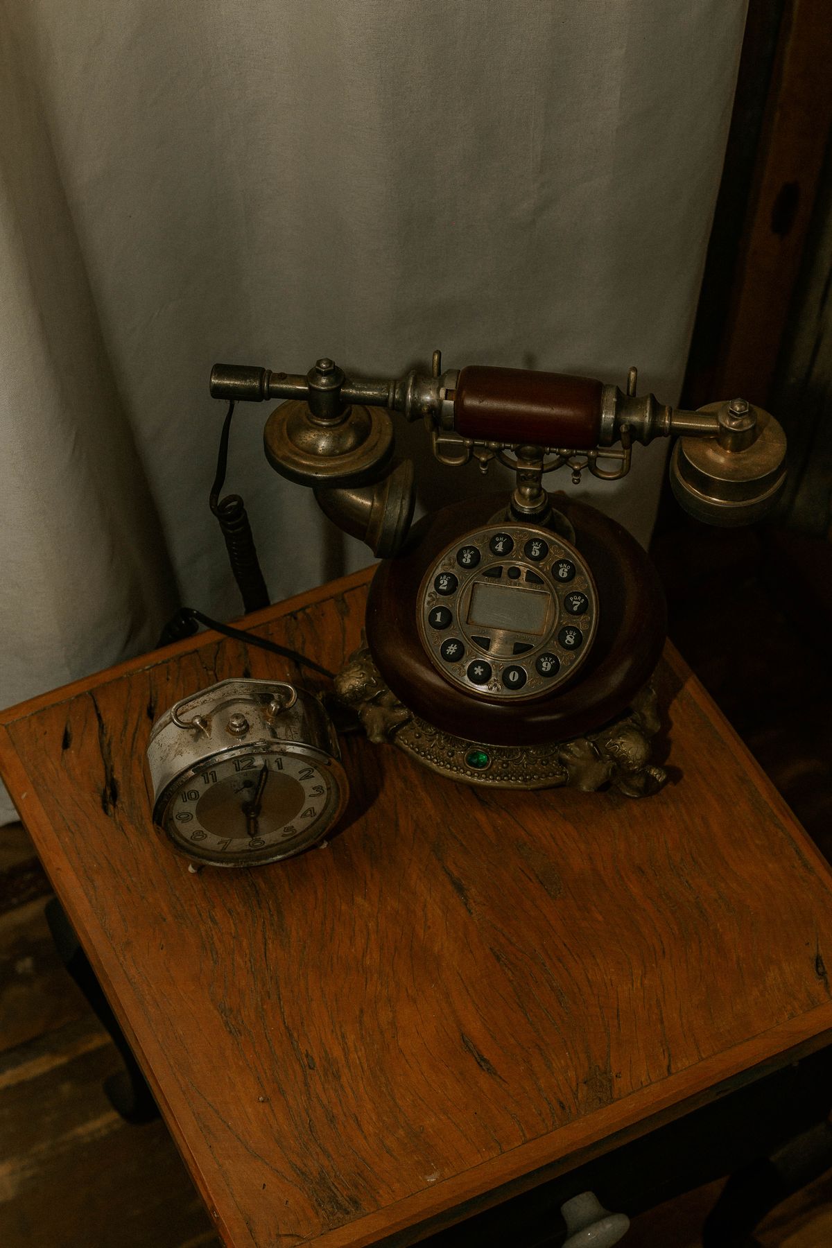 Telefone antigo e relógio despertador sobre uma mesa