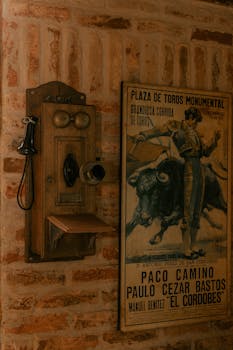 A rustic wall with bullfighting poster and antique telephone, capturing a nostalgic Spanish decor style.