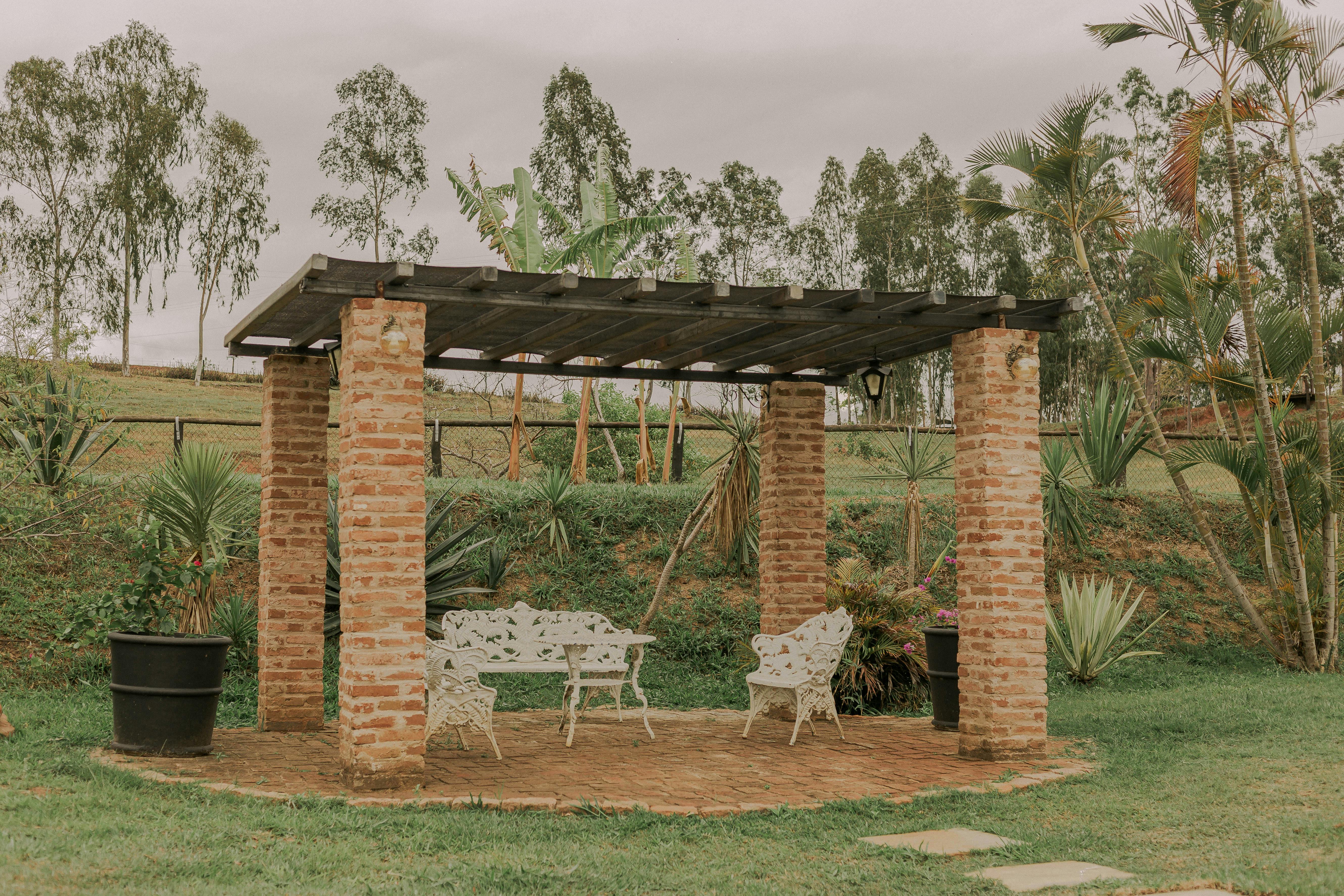 Rustic pergola with white furniture surrounded by greenery