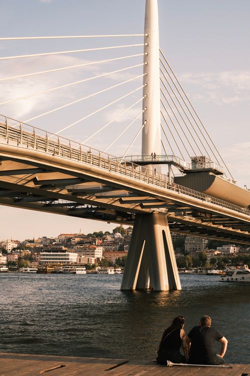 Free View of the Golden Horn Metro Bridge in Istanbul, with people relaxing by the water during sunset. Stock Photo