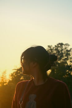 A serene silhouette of a woman against a vibrant sunset, evoking tranquility.