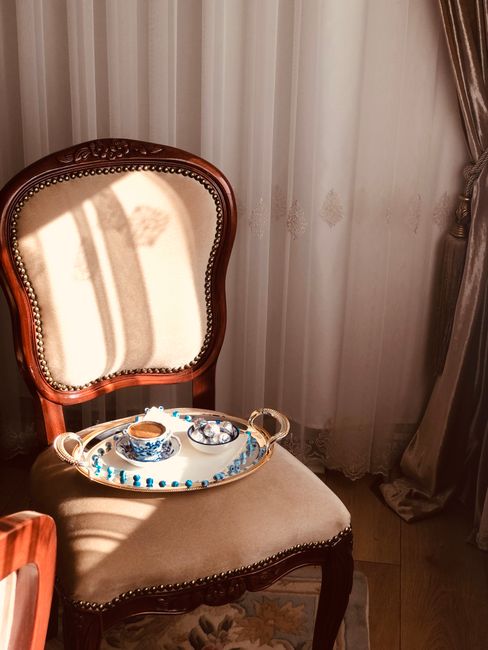 Antique chair with coffee and sweets in warm sunlight, elegant setting.