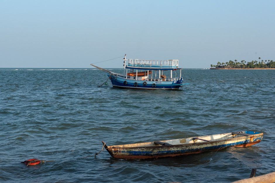 A traditional boat floats on the ocean near Porto Seguro, Brazil, under the clear blue sky.